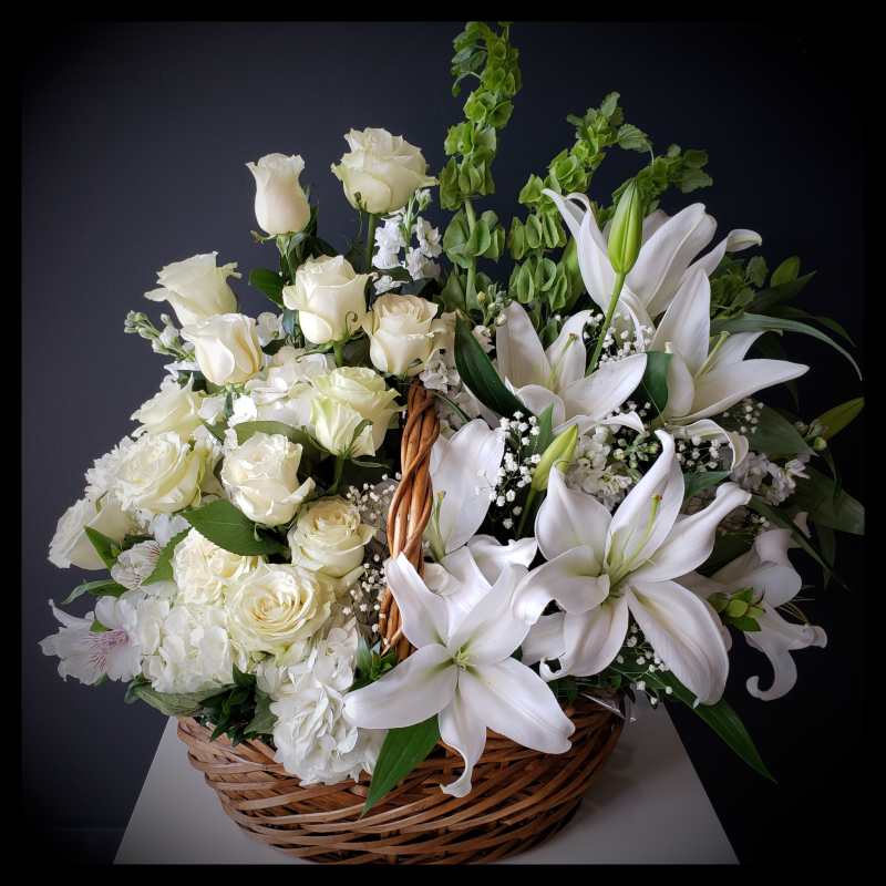 White roses and lilies arranged in a wicker basket